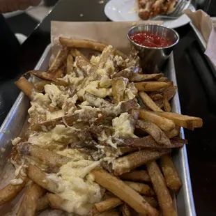 a tray of french fries with cheese and ketchup