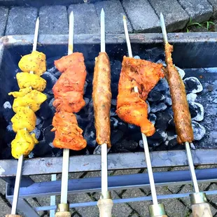 several skewers of food being cooked on a grill