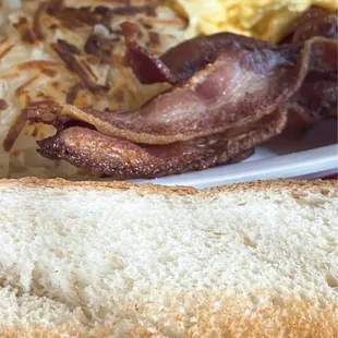 Scrambled eggs, hash browns, bacon and toast