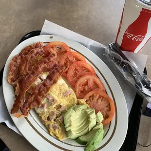 Ham and cheese omelette with onions and side of bacon and side of tomato slices and large iced tea