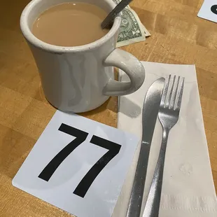 a cup of coffee and a fork and knife on a table