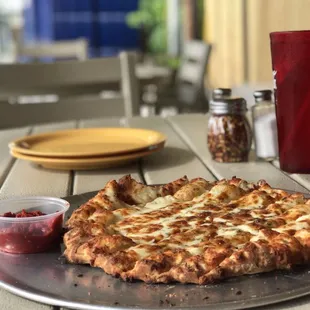a pizza on a plate with a cup of ketchup
