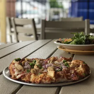 a plate of salad and a pizza on a table