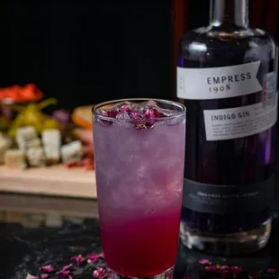 a purple cocktail with a bottle of empress