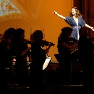  a woman in a blue dress with her arms outstretched out