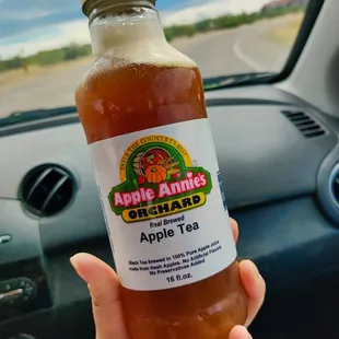 a hand holding a bottle of apple tea