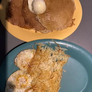 Pancakes and two eggs over medium with hash browns