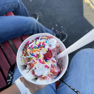 a person holding a bowl of ice cream and sprinkles