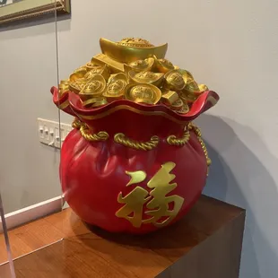 a red pot with gold coins in it