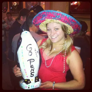 a woman in a sombren holding a penguin balloon