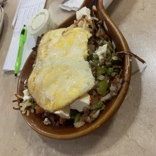 Grecian skillet ( with a couple of bites missing!). Two eggs over hard, hashbrowns, gyro meat, onions,gr peppers, tomatoes,feta cheese.