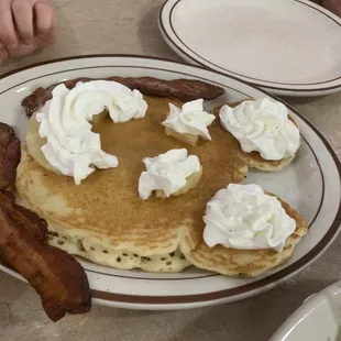 Mickie mouse pancakes with bacon, pineapple and whipped cream.