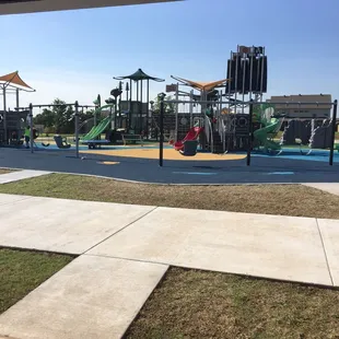 Playground with elevators, trampolines, swings, slides, benches, different age appropriate structures.