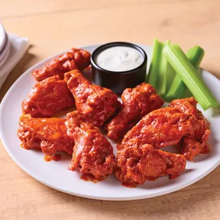 a plate of buffalo wings and celery sticks