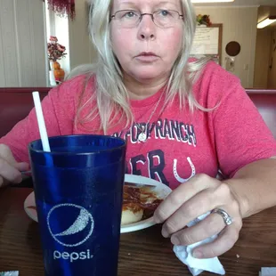 a woman sitting at a table with a plate of food and a drink