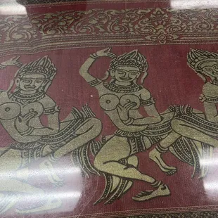 Artwork of apsara dancers on table.