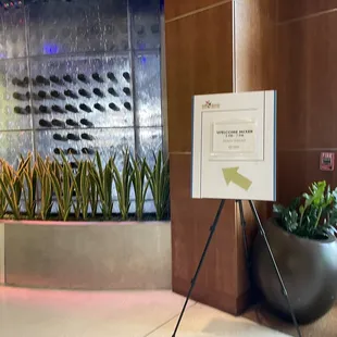 a sign in front of a wall of plants
