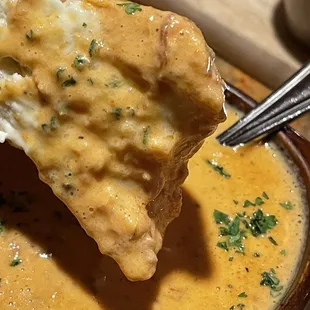 Dipping the bread in chicken red pepper soup.