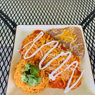 Plato de enchiladas de pollo servido con frijoles arroz y crema