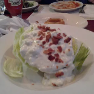 An iceberg lettuce wedge salad with bleu cheese dressing and bacon