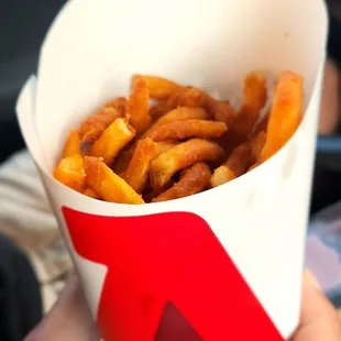a hand holding a container of french fries