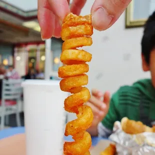 a hand holding a stack of fried donuts