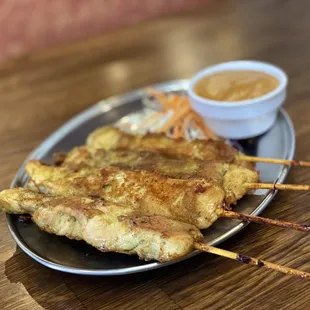chicken skewers on a plate with dipping sauce