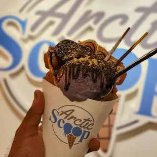 Egg waffle cone with taro Ice cream and topped it with Pocky®, Oreo®, graham cracker dust, and a chocolate drizzle.