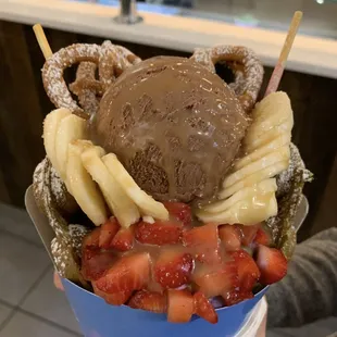 a person holding a cup of ice cream and strawberries