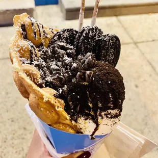 Coconut ice cream in an egg waffle cone with Oreo cookies, Pocky, chocolate chips, toasted coconut flakes, Oreo dust &amp; chocolate drizzle.