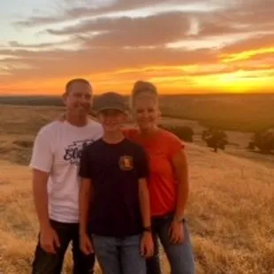 a family standing in a field at sunset