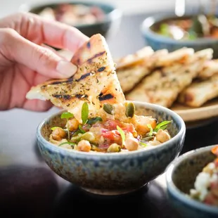 a person dipping a piece of bread into a bowl of food