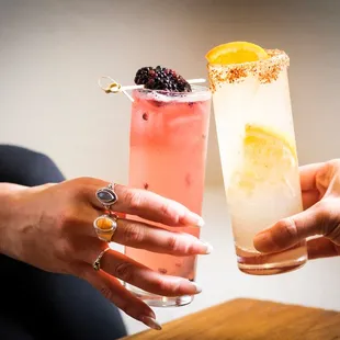 two people holding glasses of drinks