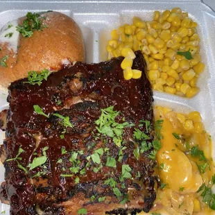 Fire braised rib dinner with corn, buttered bun and some scalloped potatoes.