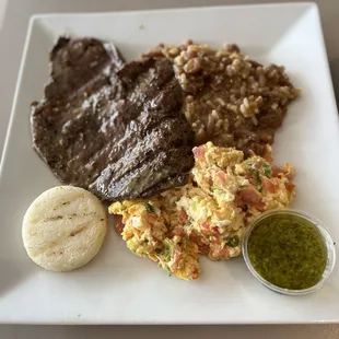 Carne Asada with rice and beans and scrambled eggs with diced tomatoes scallions and cheese