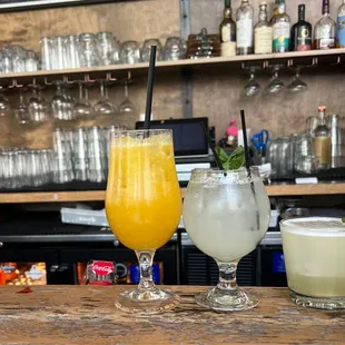 two glasses of drinks on a bar