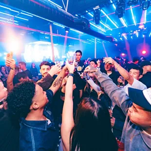 a crowd of people raising their hands in the air