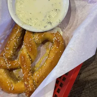 a basket of pretzels and a bowl of dip