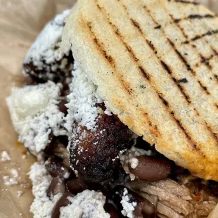 a close up of a sandwich with meat and beans