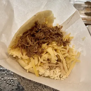 Arepa rellena de carne, pollo, queso amarillo y queso blanco.
