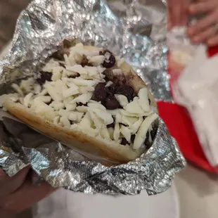 a person holding a hot dog covered in toppings