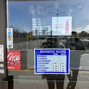 a business hours sign in the window