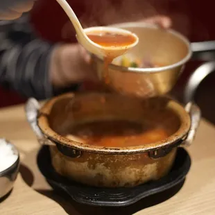 a person stirring a pot of soup