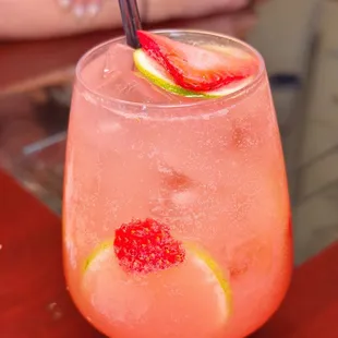 a pink drink with a straw and a slice of lime
