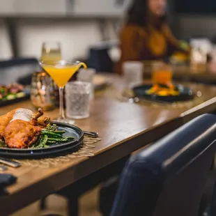 a dinner table with a plate of food and a glass of orange juice