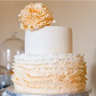 a three tiered cake with ruffles and a flower on top