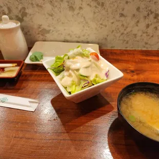 Sushi deluxe comes with soup and salad (at least with dine in). Salad is very fresh and dressing is delicious. Miso soup is good.