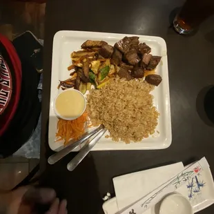 a plate of rice, meat, and vegetables