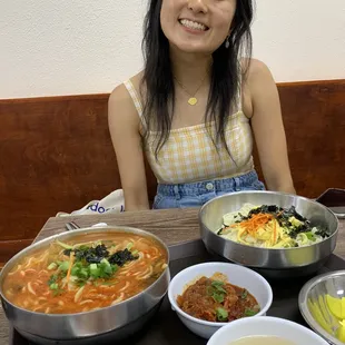 a woman sitting at a table with bowls of food