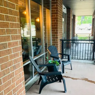 a patio with two chairs and a potted plant